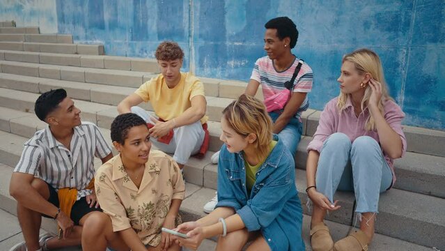 Multicultural group of teenager spending time outdoor. Multiethnic Generation z teens having fun together. Concepts about friendship and social gathering.