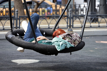 Redhead girl lying  in swing, leisure in spring park