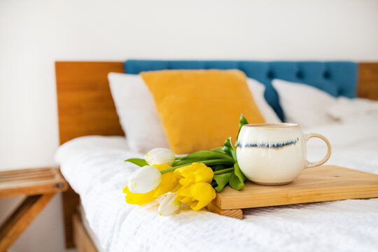 Coffee cup and bouquet of yellow tulips in bed. Concept of holiday, birthday, Women Day. Feminine flat lay. Breakfast in bed. Good morning. still life. Romantic background