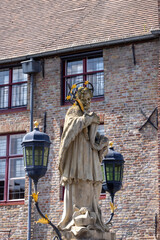 Statue of John of Nepomuk on the stone Nepomucenus Bridge over water Dijver Canal, Bruges, Belgium