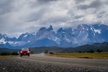 A car driving to torres del paine national park with mountains as background and beautiful sun flare (Torres del Paine, Patagonia, Chile)