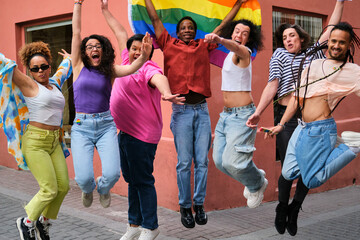 LGBTQ people are jumping up while holding a rainbow flag celebrating Pride Day. Scene is joyful and celebratory.