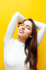 beautiful young woman with braces and in a white sweater smiling on a yellow isolated background, a...