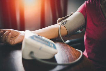 Elder woman upper arm bicep in cuff. Older retired lady measuring manually blood pressure, using...