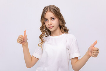 Happy smiling girl shows thumbs up looking at camera, portrait. attractive smiling girl in white...