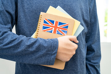 Learn English language, Asian teenage student hold book with flag in course at school.