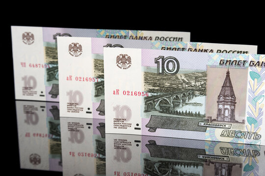 ten Russian ruble banknotes stand on a mirror surface on a black background