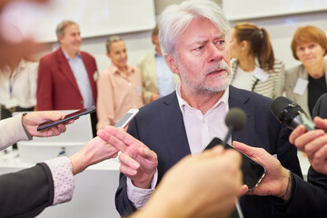 Mature speaker talking to journalists during business conference
