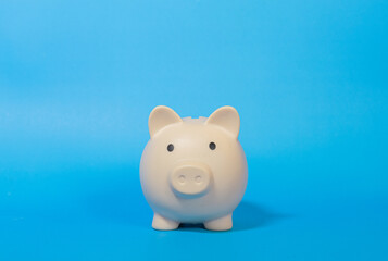 Cream color piggy bank on blue background