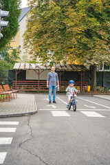 Father teaches child daughter to ride public bike on one of traffic playground in Prague, Czech republic