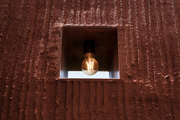 Closeup texture orange concrete wall background with light bulb. - 773922212