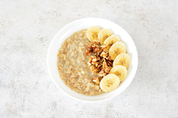 a bowl of oatmeal with bananas and nuts top view