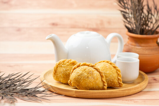 Curry puff, white teapot set isolated on white background. Samosa chicken fried curry bakery, meat, vegetable on wooden table. Yummy pie, Asian street food, Crispy snack eating with tea, coffee bread