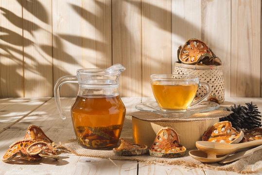 Bael Tea glass with dried bael slices on wooden background, juice perfect for detox and relaxation. Refreshing hot bael fruit tea. Tropical delight for healthy lifestyle and exotic flavors