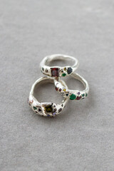 Three silver rings with natural gemstones on a gray background, highlighting their beauty. Elegant and sophisticated, perfect for special occasions.