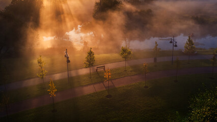 Misty Morning: Dawn Illuminating the Park's River in Fog - 773934482