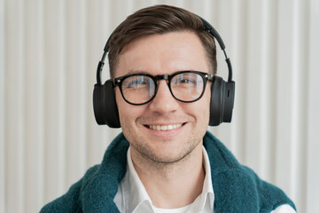 A joyous man with headphones and stylish eyewear exudes a vibrant energy, with a soft scarf...