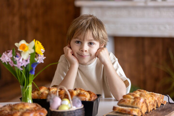 Cute preschool child, boy, holding sweet brioche bun for Easter, traditional swee bread baked with...