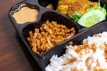 Indonesian meal box called uduk placed on the wooden table.