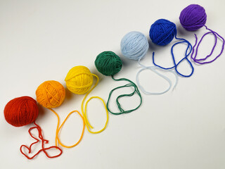 Set of the balls of threads in the rainbow colors for hand knitting arranged in a row on a white table, background

