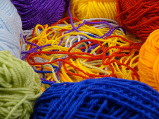 Multi-colored threads for knitting in a tangled state and skeins of yarn, background
