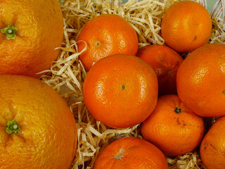 Fresh tangerines and grapefruits lie on the decorative straw, a delicious gift