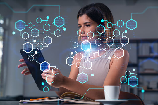 Smiling businesswoman in casual wear holding tablet device touching it at office workplace. Concept of distant work, business education, information technology.Blockchain hologram