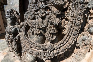 Detail of the intricately carved ornamentation on the sculpture of a guardian deity at the ancient Hoysaleshwara temple complex in Halebidu in Karnataka.