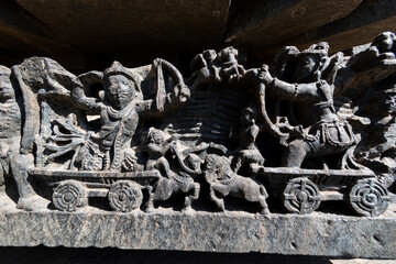 Detail of an ornate relief depicting a war scene on the wall of the ancient Hoysaleshwara temple in Halebeedu. - obrazy, fototapety, plakaty