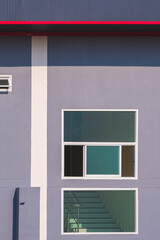 Glass windows on gray cement wall near the stairway inside of modern industrial office building in vertical frame