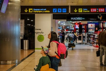 MUJER CON NI&Ntilde;O MIRANDO LAS PAMNTALLAS DEL AEROPUERTO