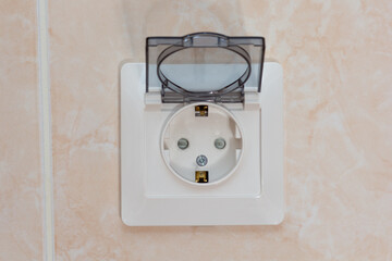 Socket for two-pin plug with cover on light brown wall