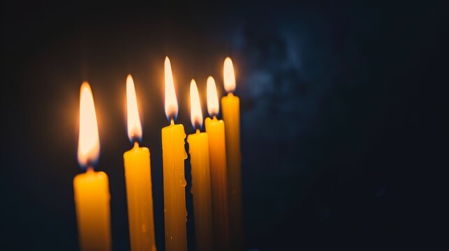 A row of candles are lit and are arranged in a straight line. The candles are yellow and the image has a warm and cozy feeling