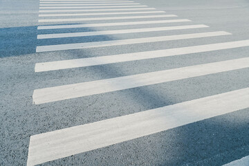 Fototapeta premium pedestrian crossing, white stripes on black asphalt, road markings zebra crossing, place to cross the road, traffic rules