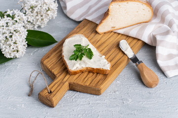 Cream cheese with herbs and seasoning on slice of fresh crunchy rye bread with cheese knife nearby