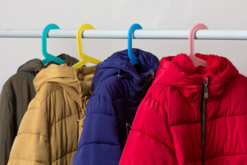 Rank of puffer coats hanging over white background