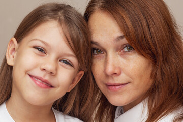 Portrait of mother and daughter hugging and looking at camera