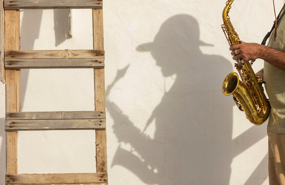 Anonymous saxophonist Shadow on Urban Wall in Daylight
