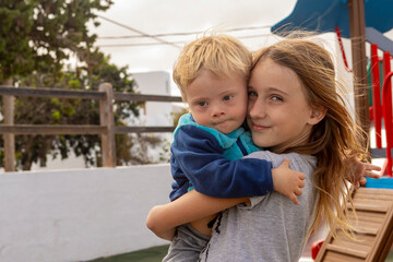 Sibling love at the playground with a Down syndrome toddler