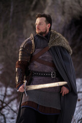 Medieval knight with sword in armor as style Game of Thrones in winter forest - 773975222
