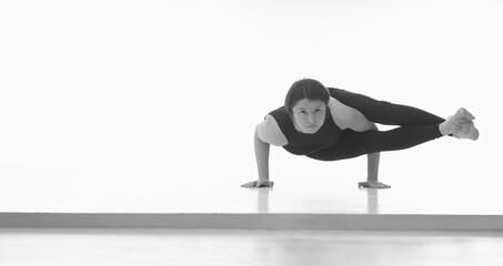 Astavakrasana, Ashtanga yoga  Side view of woman wearing sportswear doing Yoga exercise against white background. Copy space for text or design. Horizontal black and white image.