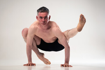 EkaPada Bakasana, Ashtanga yoga  Side view of man wearing sportswear doing Yoga exercise against white background.
