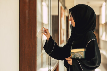 Muslim niqab woman read and learning the Quran and faith The Holy Al Quran book. Arab saudi black chador lady.