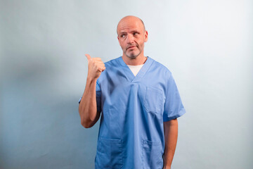 Portrait of a physiotherapist in light blue gown pointing at a side.