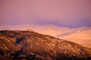 Views of Sierra Nevada from Granada during the golden hour at sunset with the peaks full of snow.