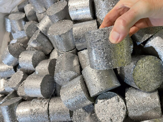 hand holding an aluminium puck which is compressed swarf ready for recycling