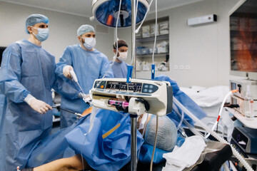 A group of medical surgeons in the operating room during an operation. A patient on the operating table during laparoscopic abdominal surgery. The concept of modern medical equipment. - obrazy, fototapety, plakaty