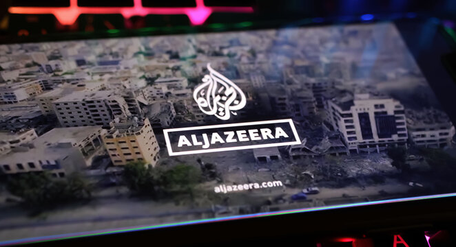 Viersen, Germany - April 1. 2024: Smartphone screen on computer keyboard with logo lettering of Al Jazeera arabic television with Gaza Israel conflict report