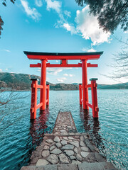 Torii of Hakone Shrine at Lake Ashi in the Hakone area of Kanagawa Prefecture in Honshū, Japan. Traditional red Japanese gate in the crater lake.