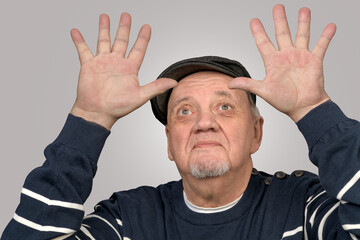 portrait homme âgé avec béret les mains levées sur fond gris - 774003638